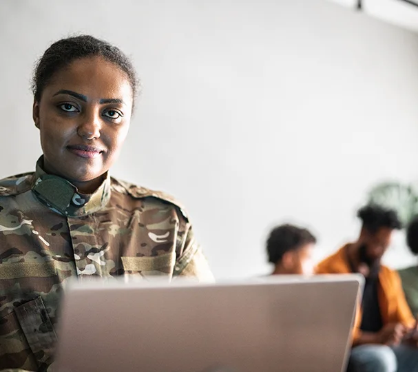 Veteran woman smiling while looking at job opportunities on her laptop.