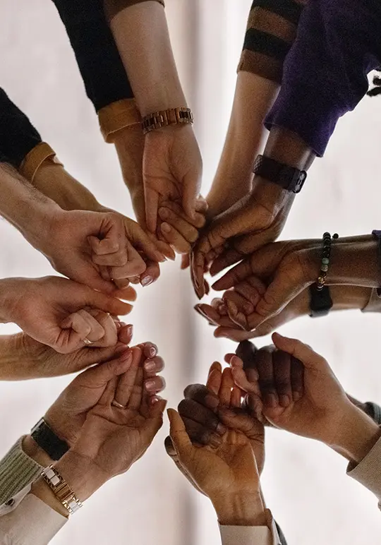 Lots of people from different backgrounds holding each others hands, forming a circle.
