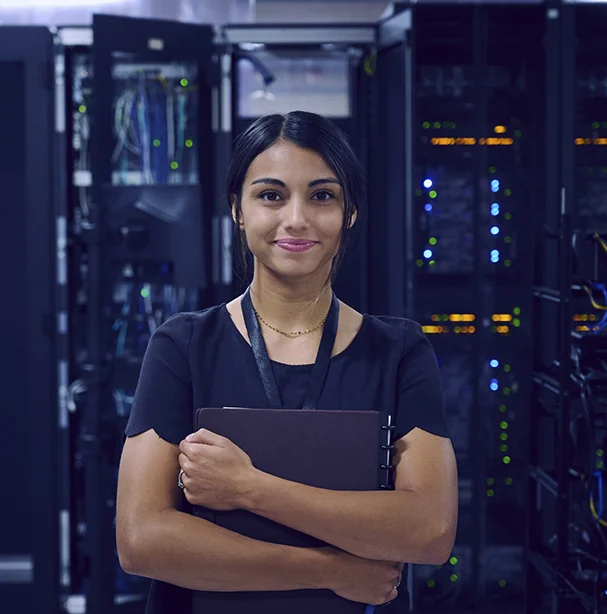 Young woman smiling with confidence in a busy computer server room.