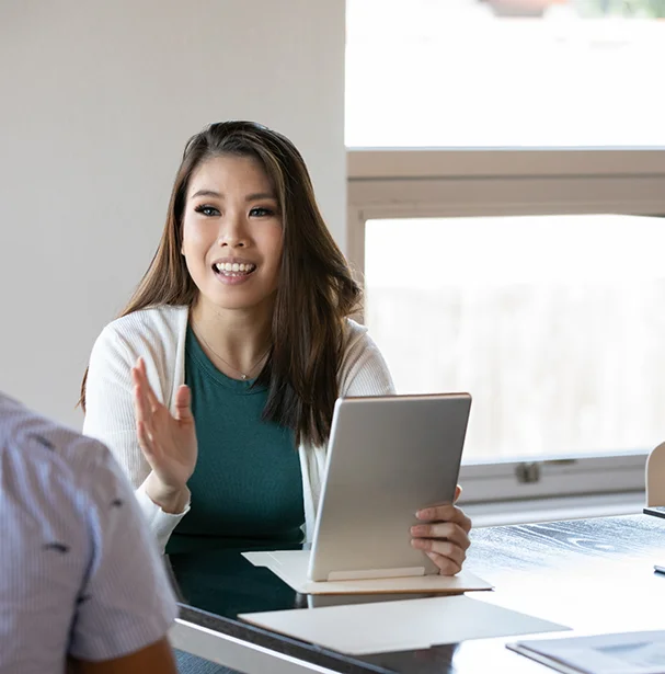 Woman holding ipad in office explaining something.