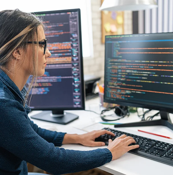 Woman entering data on two computers.