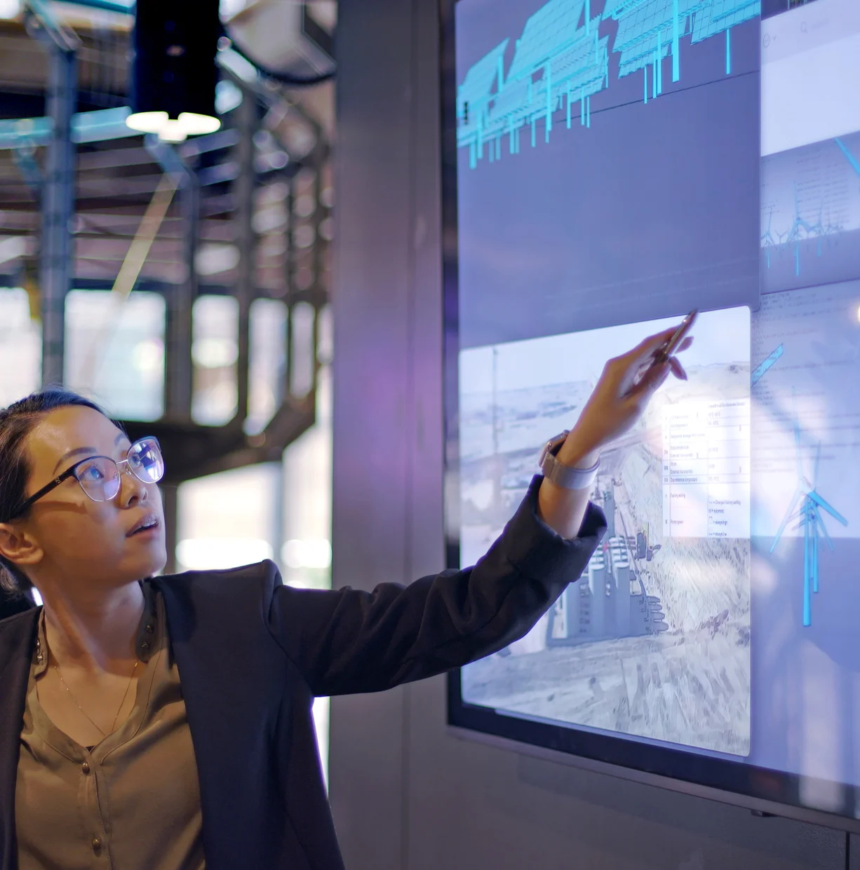 Young woman pointing at a model projected on wide screen while doing a presentation.